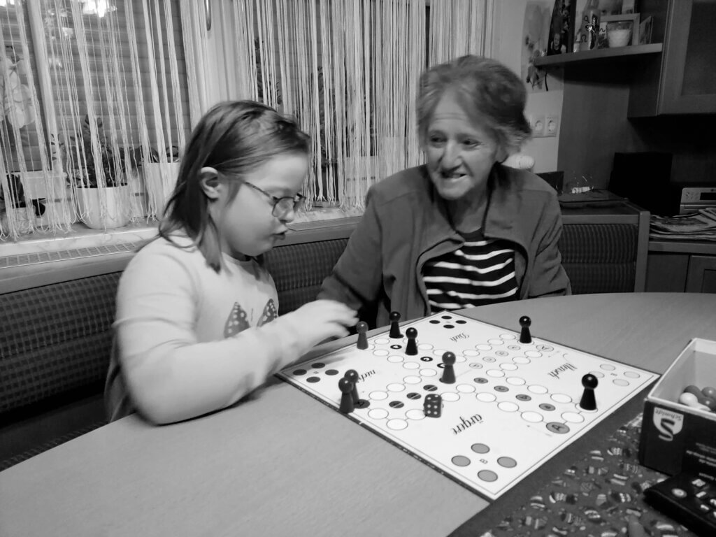 Ein schwer-weiß-Foto. Lisa mit ihrer Großmutter beim Mensch-ärgere-dich-nicht-Spielen.
