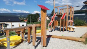 Der Soielplatz mit verschiedensten Klettergerüsten und einer Rutsche. Sie ist aus Holz gebaut mit vielen roten Details.