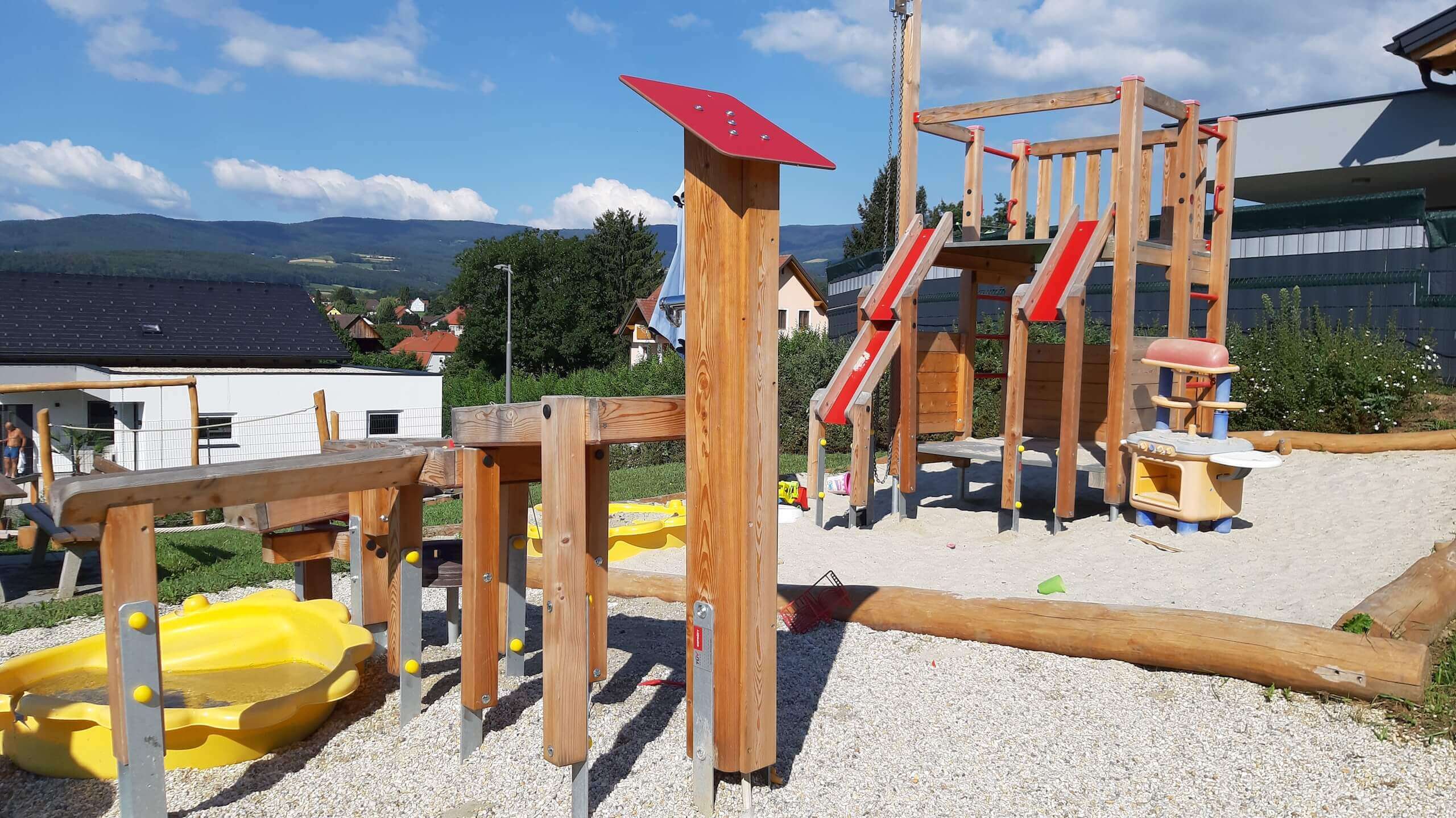 Der Soielplatz mit verschiedensten Klettergerüsten und einer Rutsche. Sie ist aus Holz gebaut mit vielen roten Details.