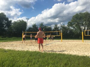 Ein paar Jugenliche beim Volleyballspielen am Platz im Sonnenschein.