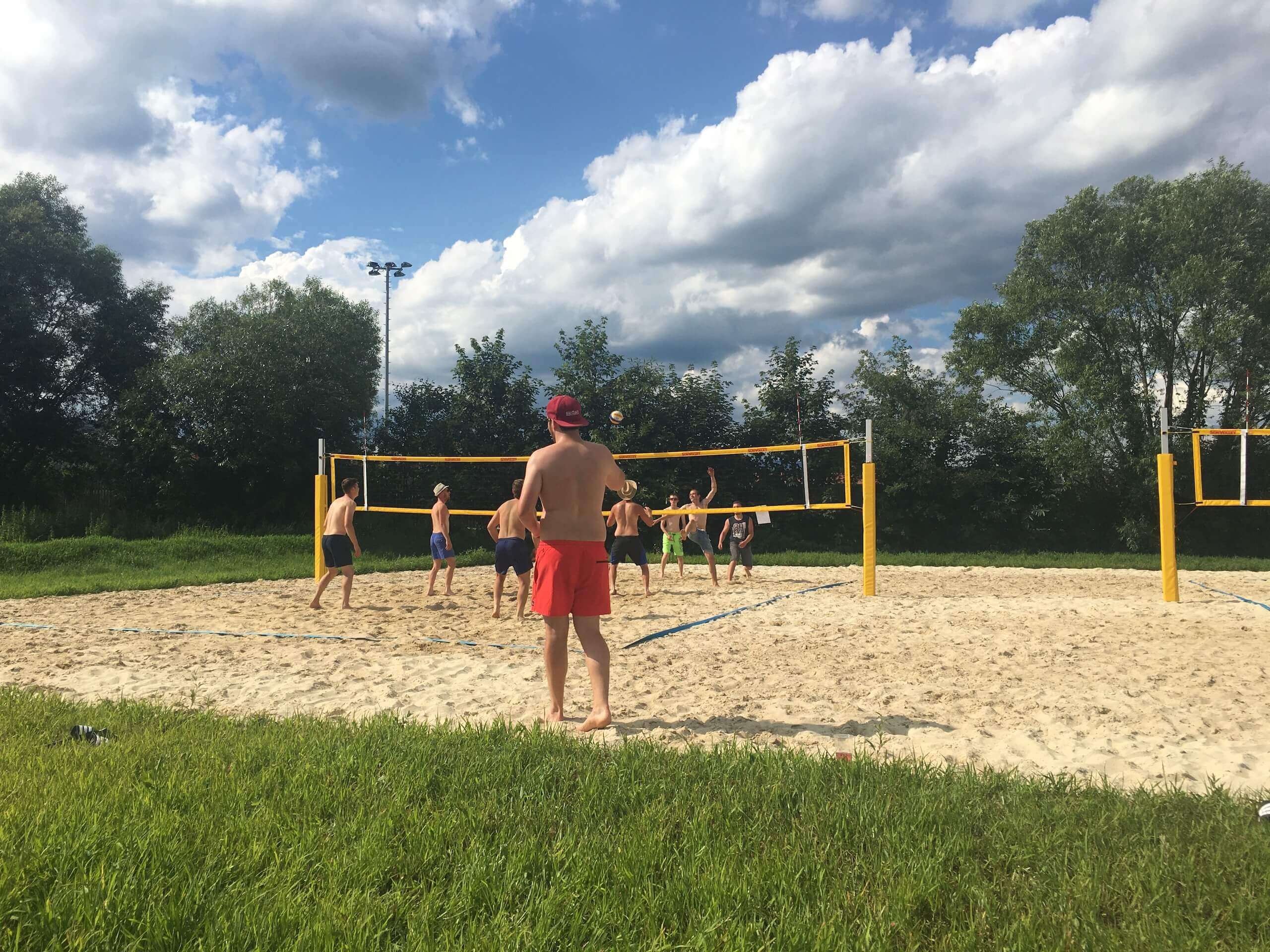 Ein paar Jugenliche beim Volleyballspielen am Platz im Sonnenschein.