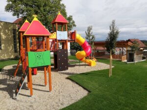 Der Spielplatz in Greinbach besteht aus einem bunten Klettergerüst mit kleinem Dach und einer rot-gelben Rutsche.
