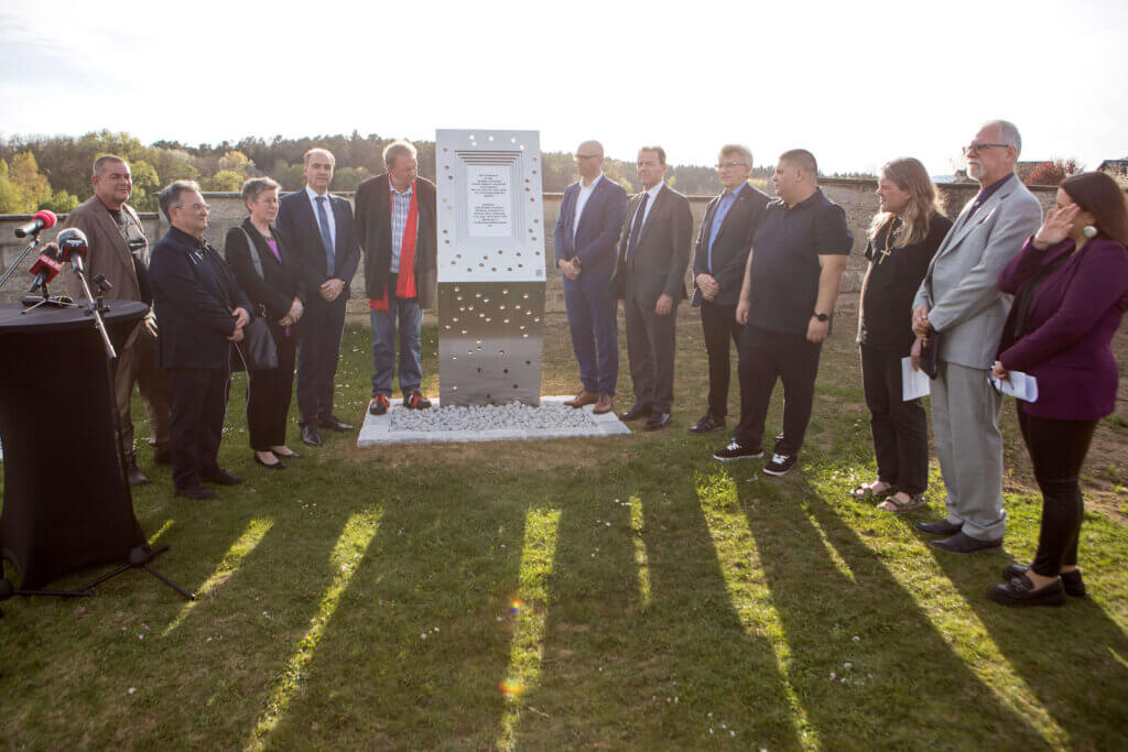 Landesrat Dr. Leonhard Schneemann (4.v.l.) bei der Enthüllung der Gedenktafel am Friedhof im Ortsteil Kitzladen. Um die gedenkstätte sind zahlreiche Menchen versammelt, die in die Kamera blicken