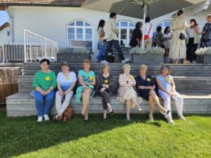 Es herrscht gute Stimmung bei den Gästen - der Zonta Club Szomathely wurde fotografiert, sieben Damen waren als Vertretung da. sie sitzen auf den Holztreppen die gleichzeitg eine Sitzgelegenheit der grau-braunen Terrasse ist.