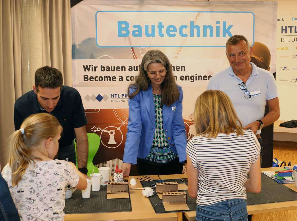 Die Bautechnik-Abteilung der HTL Pinkafeld. Am Bild sind Lehrende und interessierte Schülerinnen, die interessiert auf einen Tisch mit Gegenständen blicken