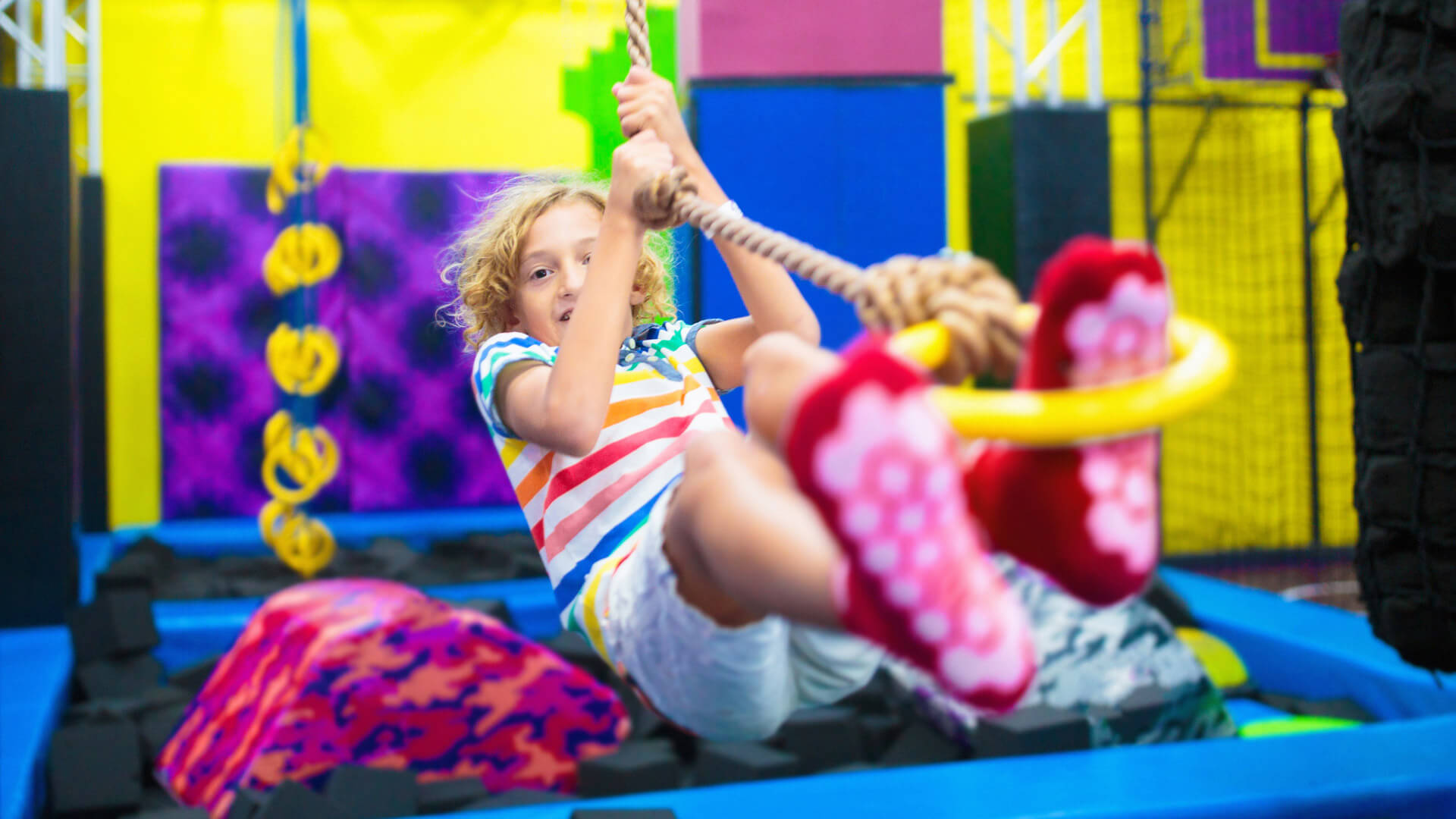 Ein Mädchen hält sich mit den Händen an einem Seil fest und springt auf einem Trampolin.