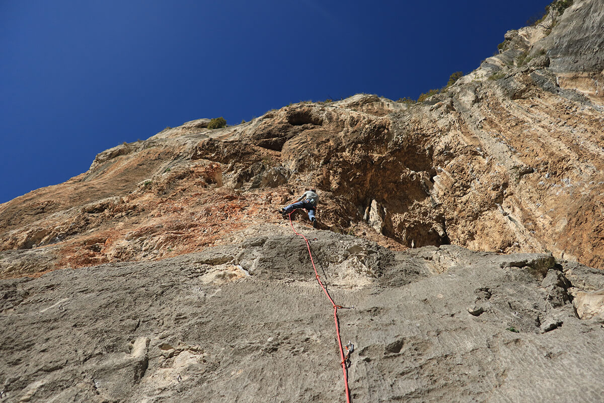 Kletterer bezwingt steile Felswand unter klarem Himmel - Abenteuer und Outdoor-Sport erleben.