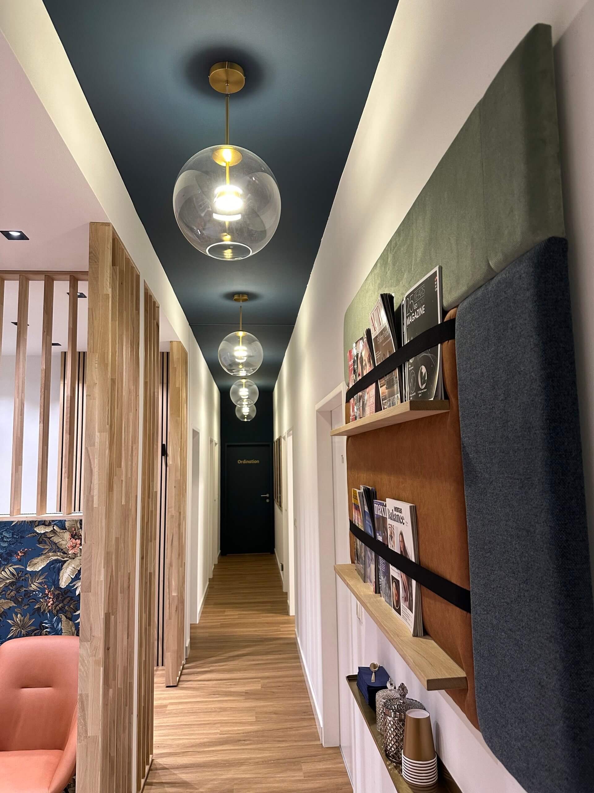 Moderner Flur mit hängenden Kugelleuchten, Holzboden und Zeitschriftenregal an der Wand.