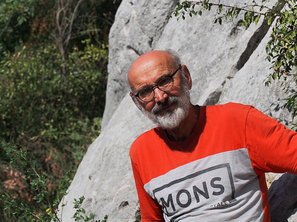 Älterer Mann mit Bart und Brille vor Felswand in rotem Shirt in natürlicher Umgebung. Outdoor-Portrait.