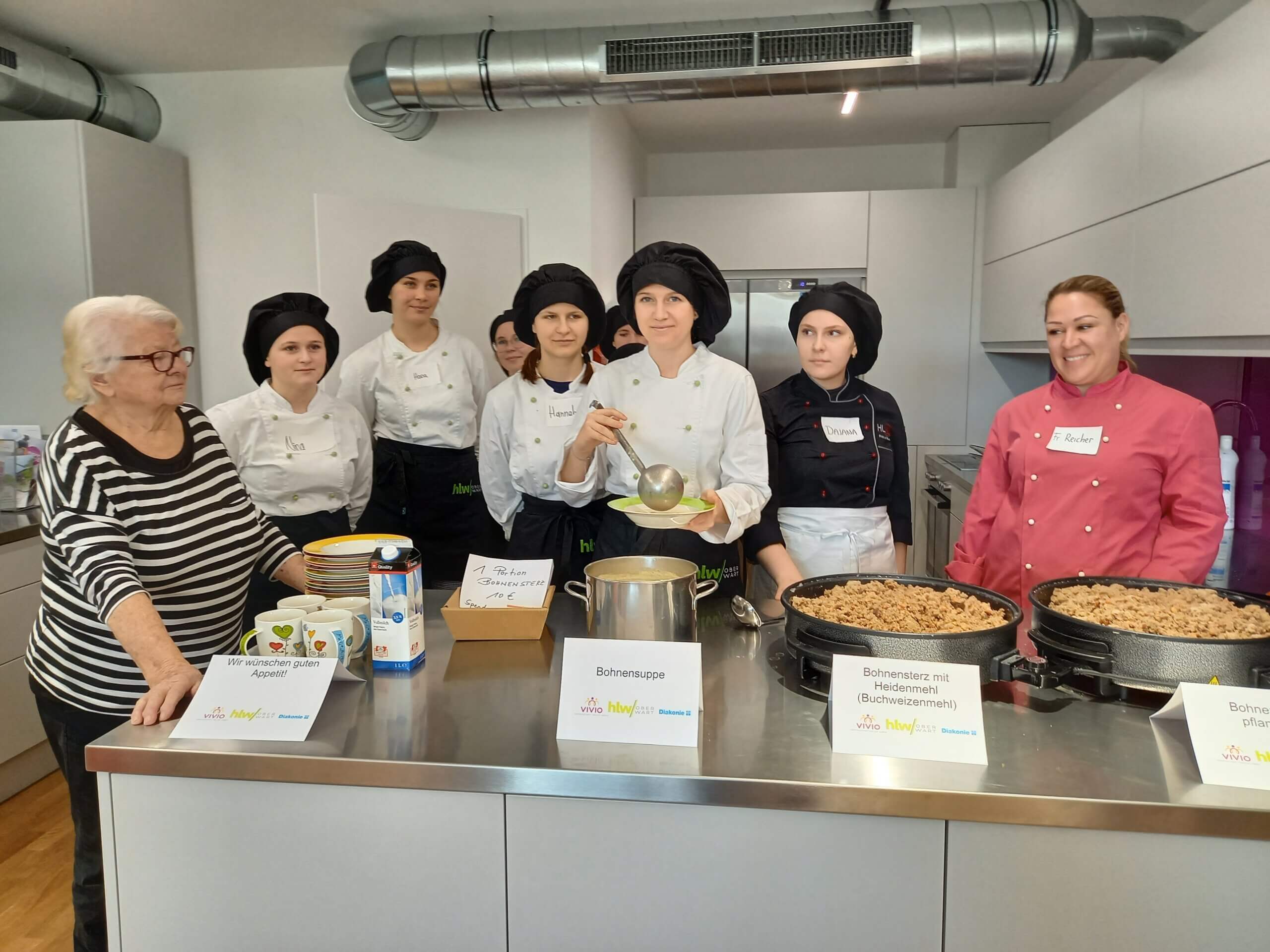 Gruppe von Köchinnen serviert Bohnensuppe und Bohneneintopf in einer modernen Küche.