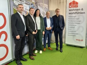 Personengruppe bei OSG-Event vor Werbebanner zu Wohnen & Wohlfühlen Dienstleistungen, Österreich.