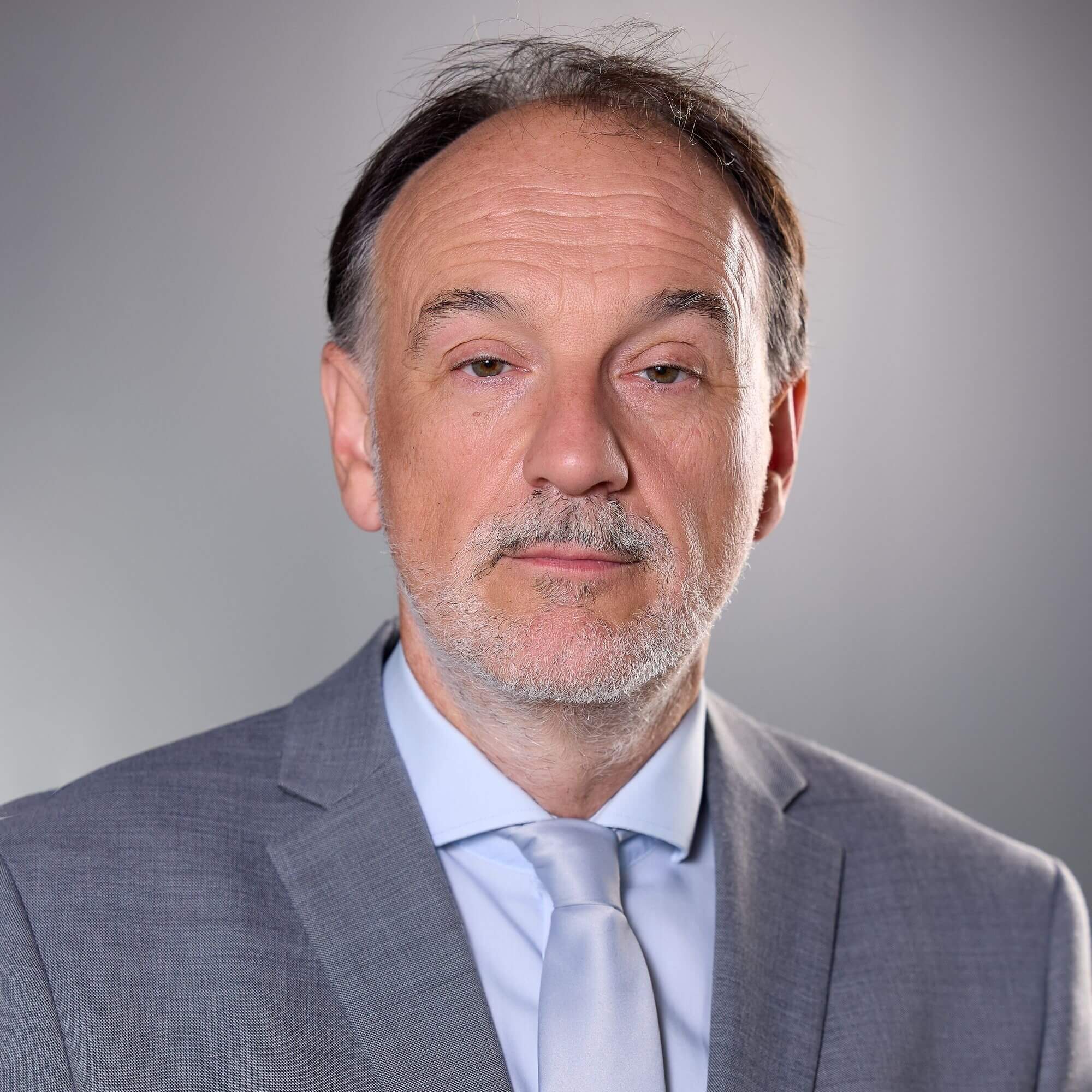 KFV_Armin Kaltenegger©KFV_APA_Fotoservice_Schedl Älterer Mann in grauem Anzug vor neutralem Hintergrund – professionelles Porträtfoto für Geschäftskontext.