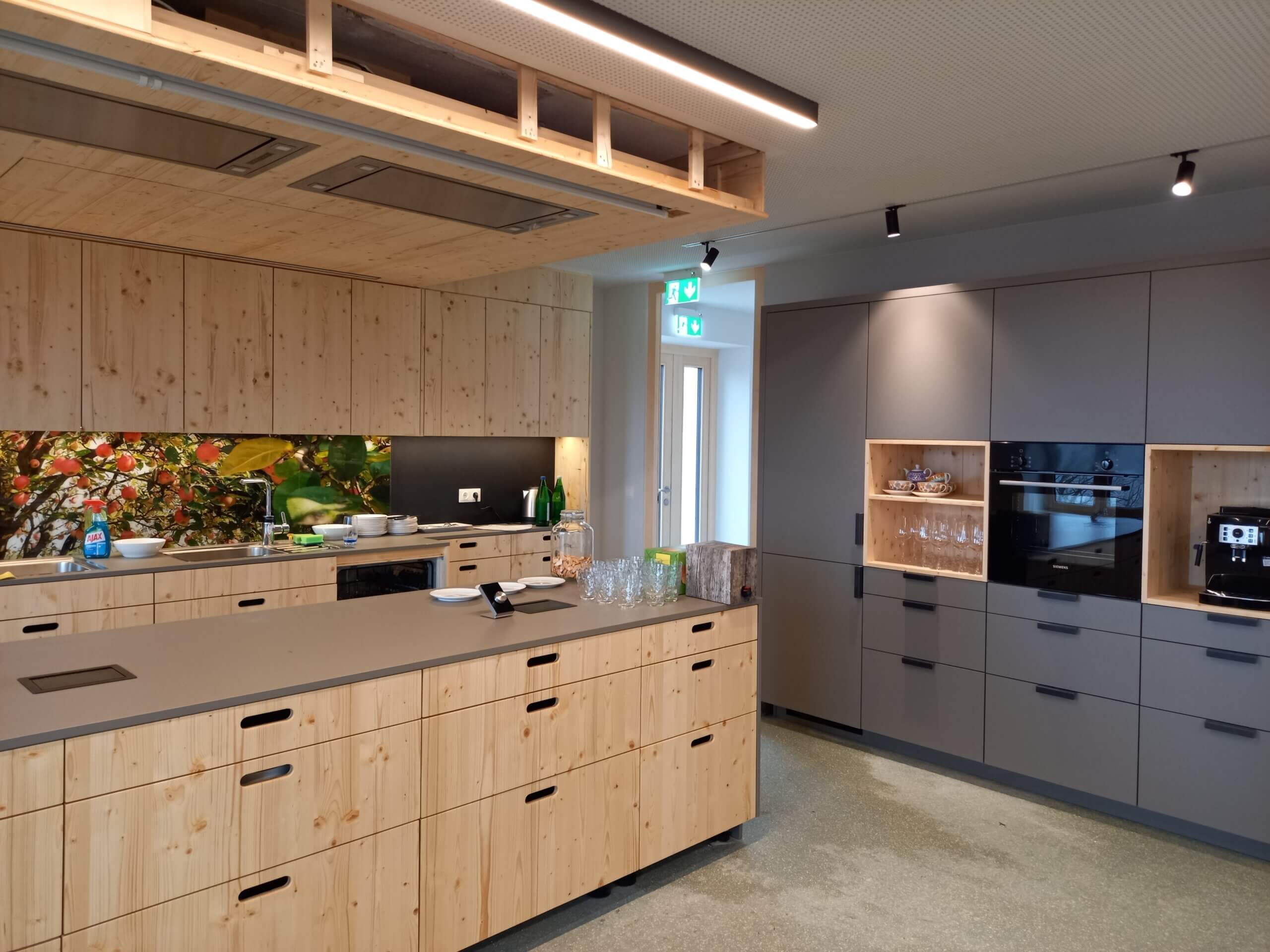 Moderne Küche mit Holzschränken, grauen Geräten und bunter Rückwand. Stilvolle, funktionale Küchenlösung.