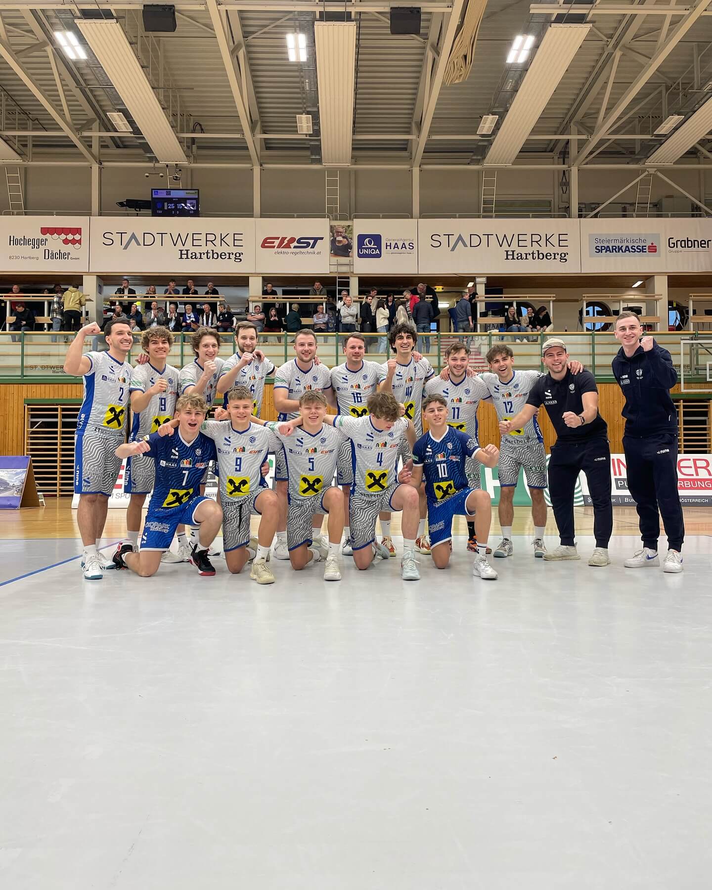 Eine Basketballmannschaft feiert auf dem Spielfeld nach einem Sieg in einer Sporthalle.