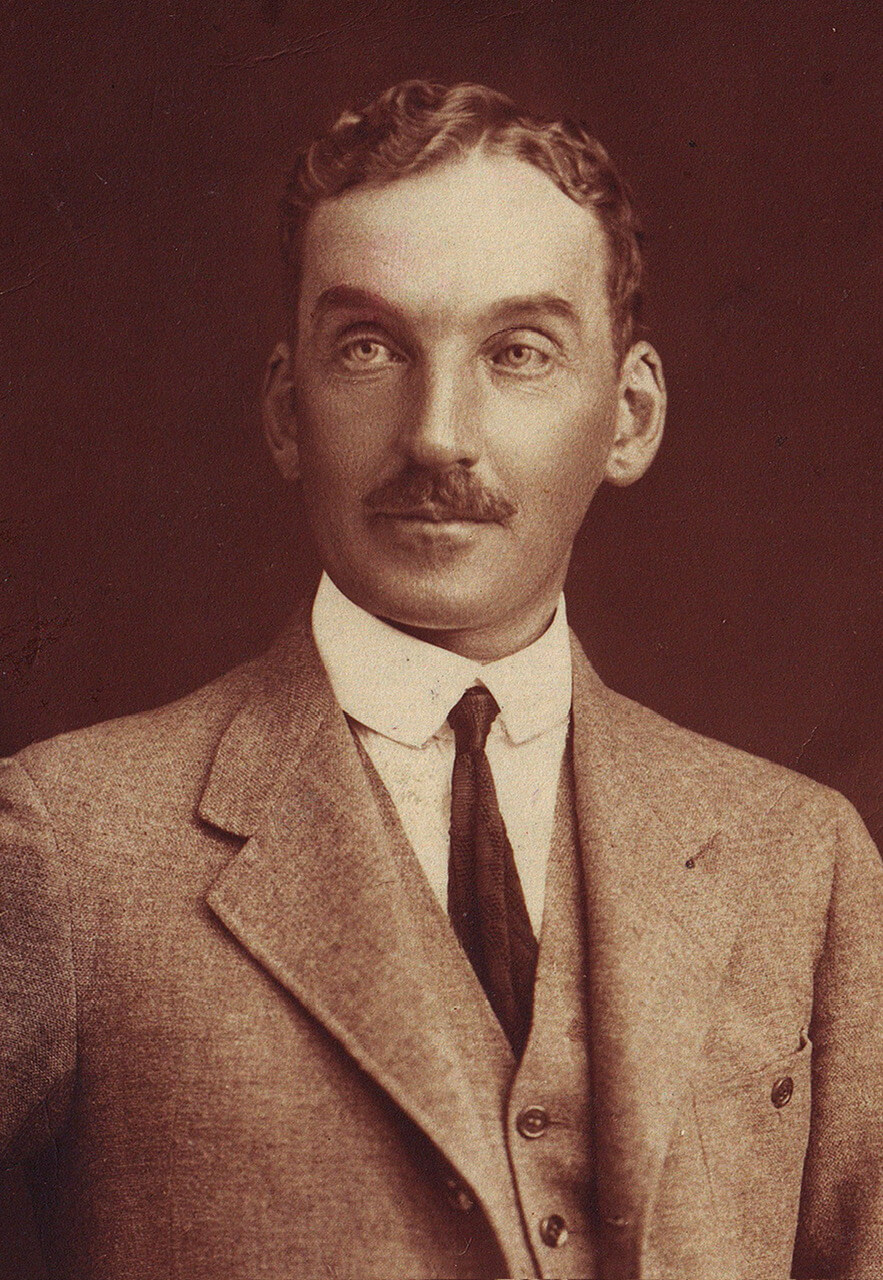 Porträt eines Mannes in einem Anzug aus der frühen 1900er-Jahre, mit klassischem Stil und nachdenklichem Ausdruck.