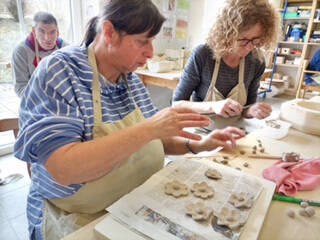 Personen formen Tonblumen in einem Keramikkurs, Handwerk und Kreativität im Vordergrund.