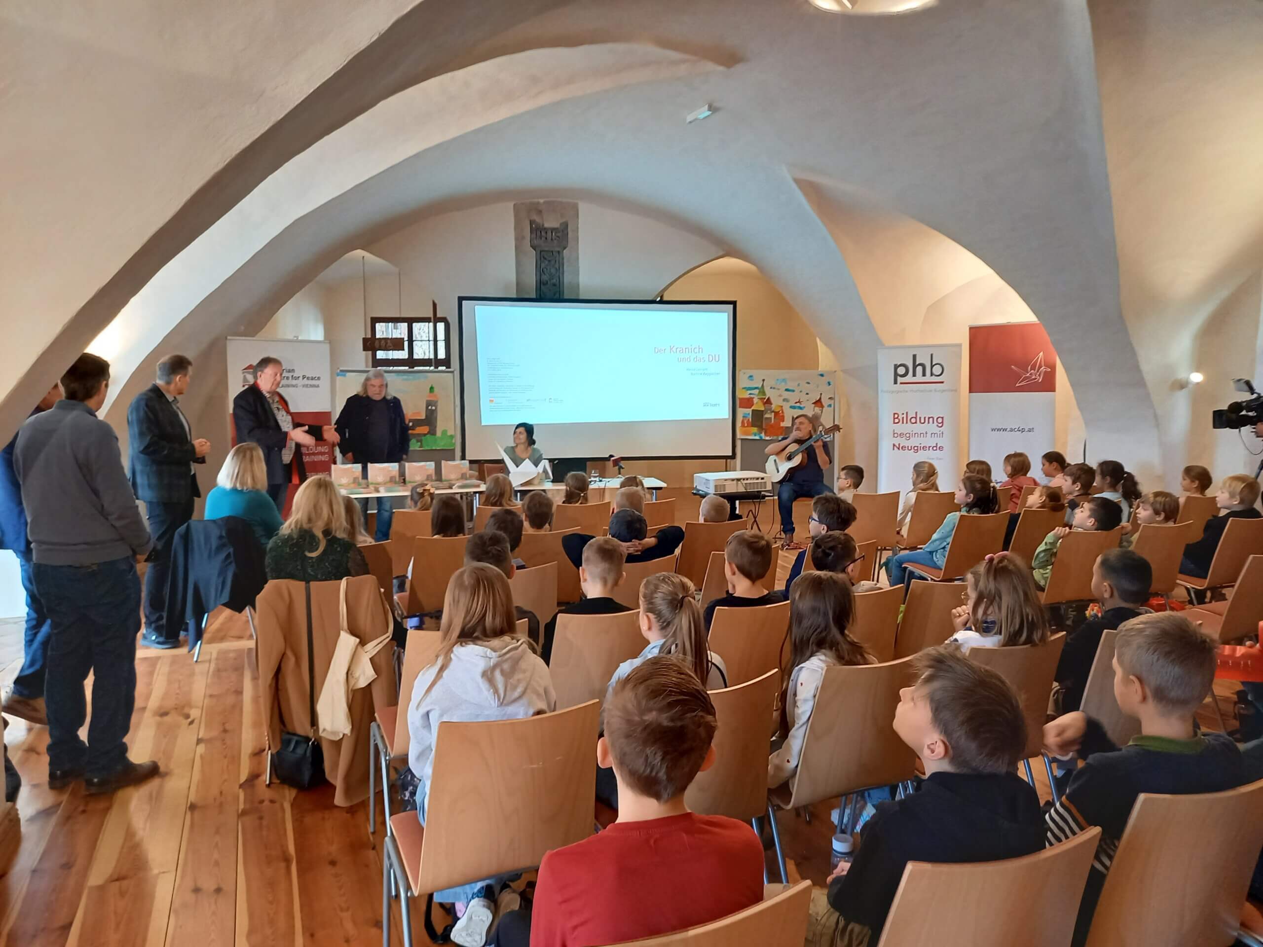 Bildungspräsentation für Kinder in historischer Halle mit Vortrag und Gitarrenmusik. Interaktive Lernerfahrung.