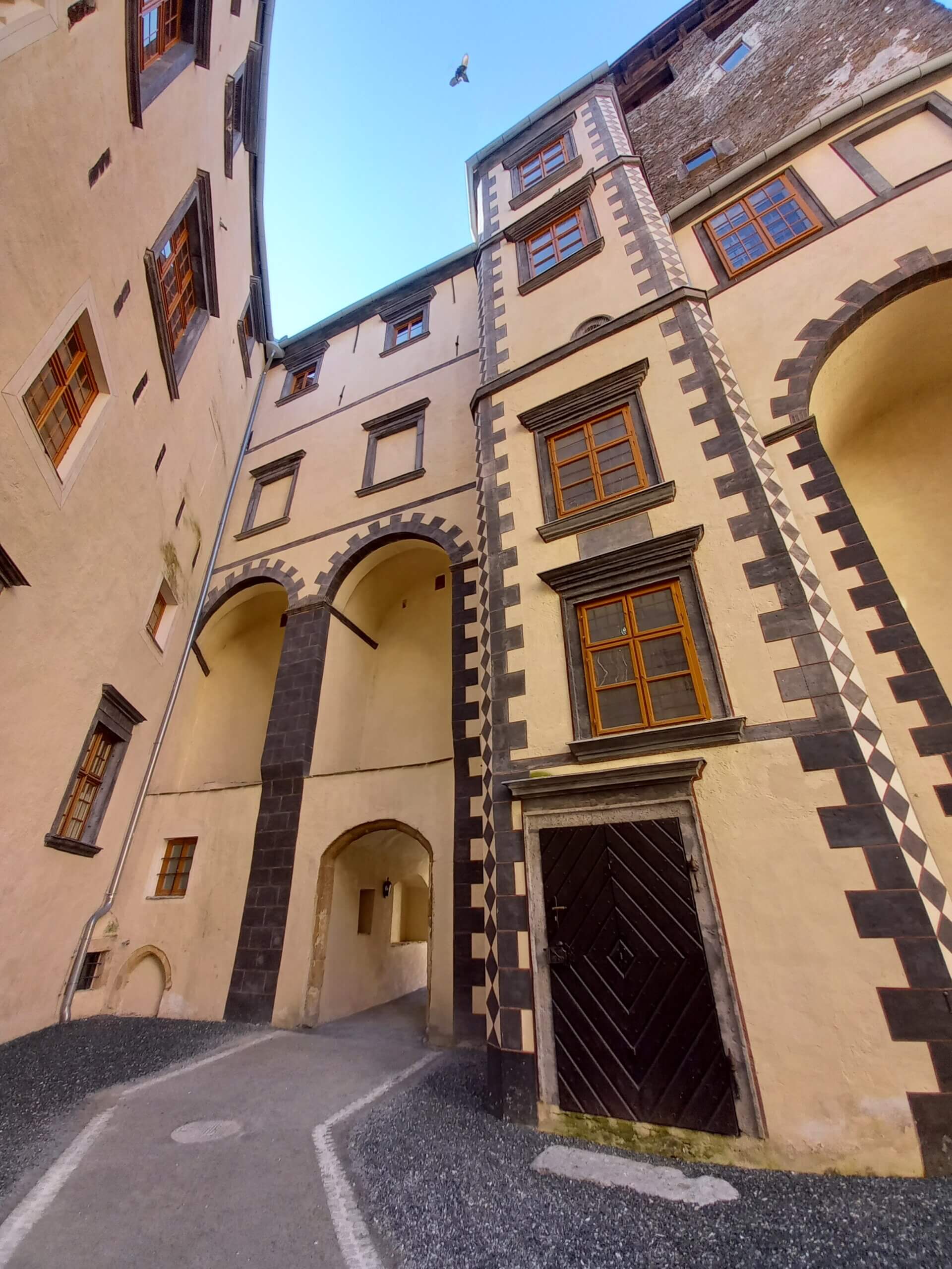 Historisches Gebäude mit verzierten Bögen und Fachwerkdetails, beeindruckende Architekturansicht von unten.