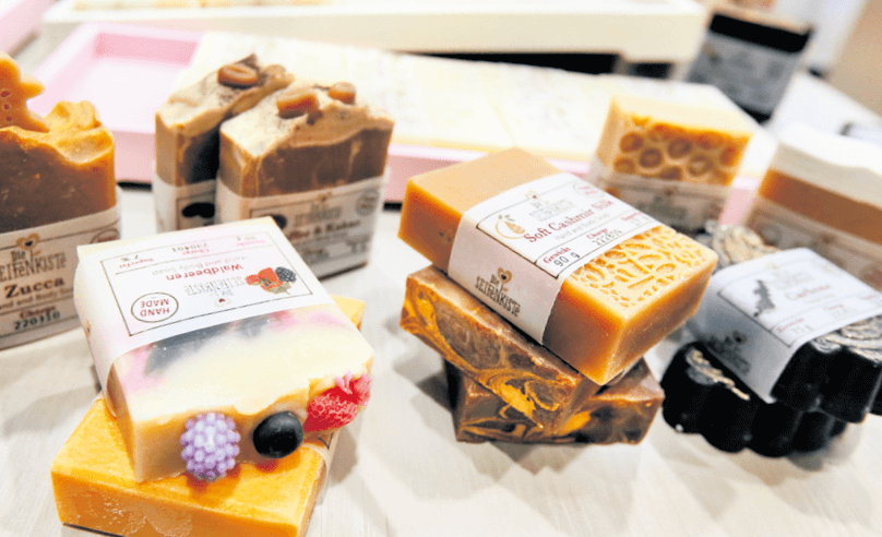 Verschiedene handgemachte Seifenstücke auf einem Tisch, farbenfroh und luxuriös arrangiert für Beauty und Pflege.