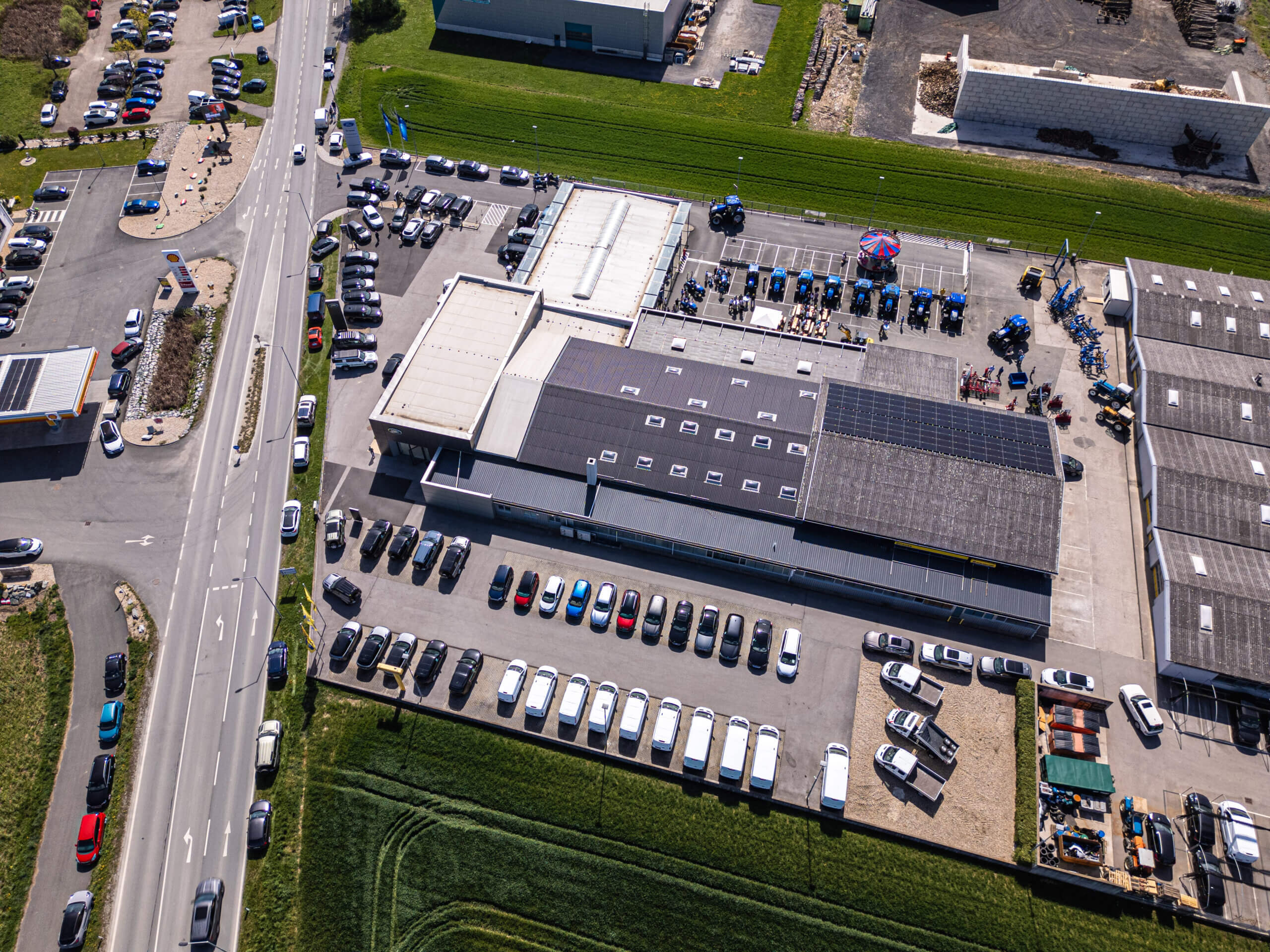 Luftaufnahme eines Industriegebiets mit Parkplätzen und Solaranlagen auf den Dächern, umgeben von Straßen.