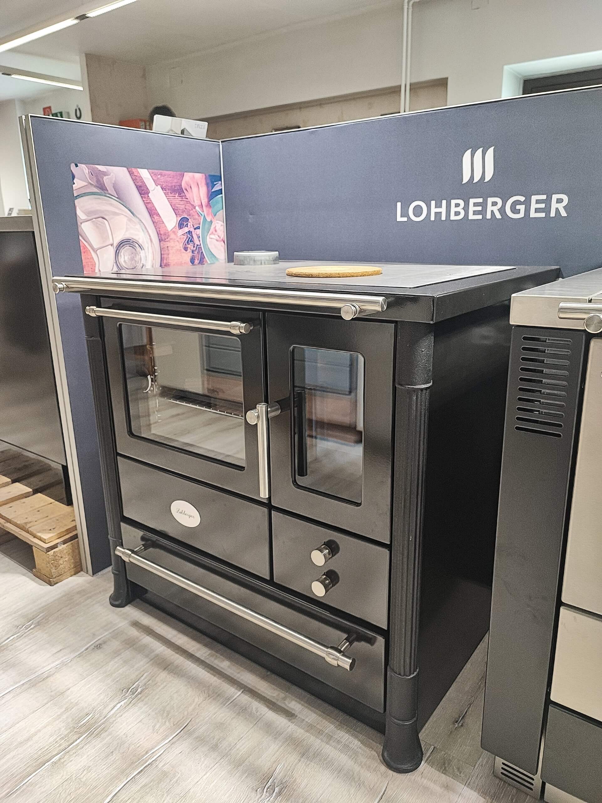 Moderner schwarzer Küchenofen mit Glastüren, silbernen Griffen und Markenlogo in einem Ausstellungsraum.