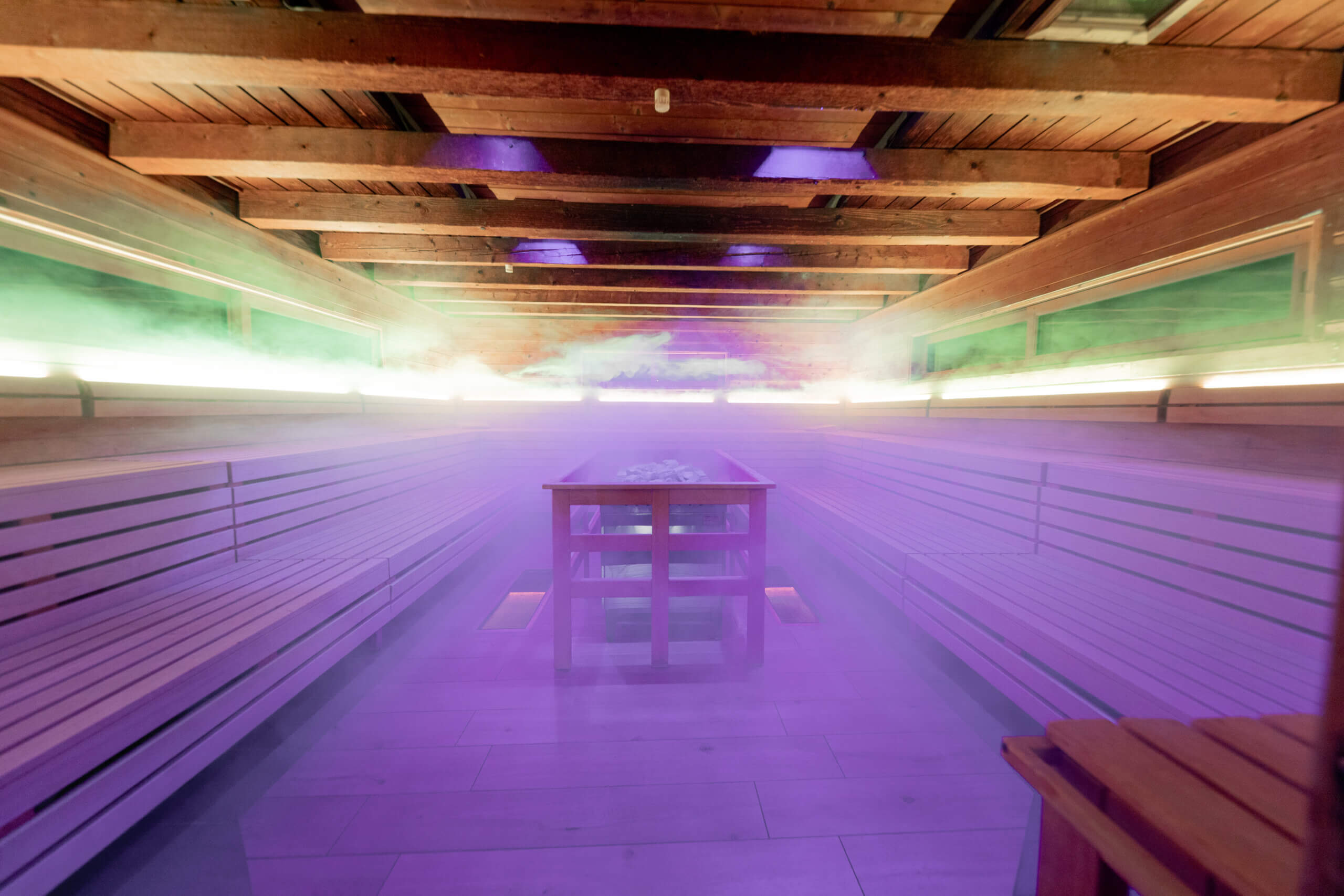 Moderne Sauna mit lila Licht und Dampf, einladend zum Entspannen und Wohlfühlen.