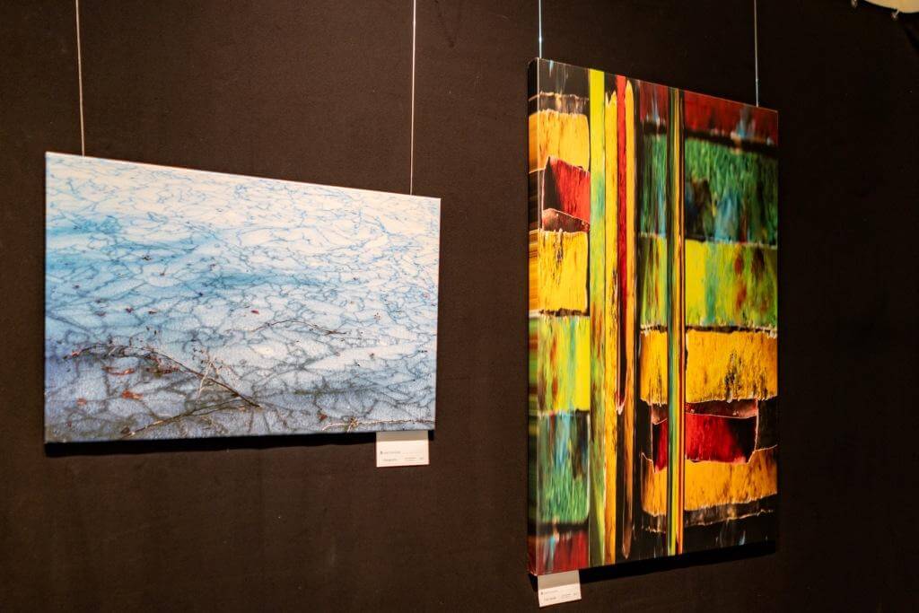 Zwei moderne Kunstwerke an einer Galerie-Wand: links in Blautönen, rechts in bunten, kräftigen Farben.