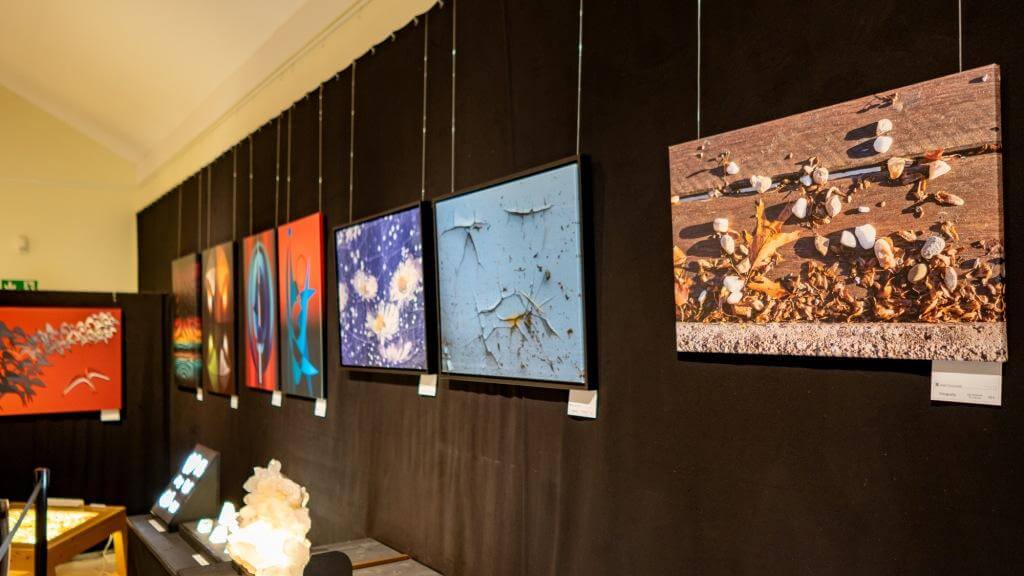 Kunstgalerie mit abstrakten Gemälden auf schwarzer Wand ausgestellt, verschiedene bunte und kreative Designs.