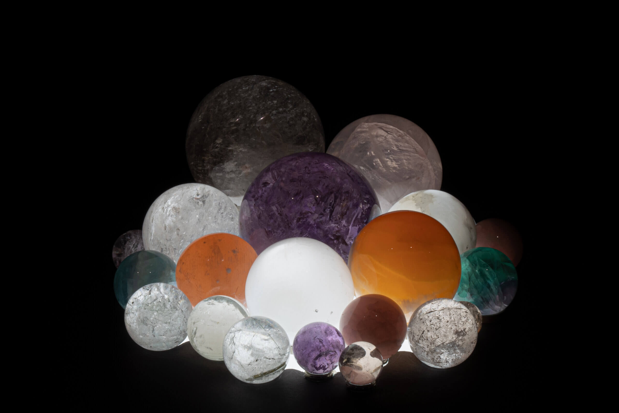 Bunte und leuchtende Glaskugeln in verschiedenen Größen auf dunklem Hintergrund. Ideal für Sammler und Dekoration.