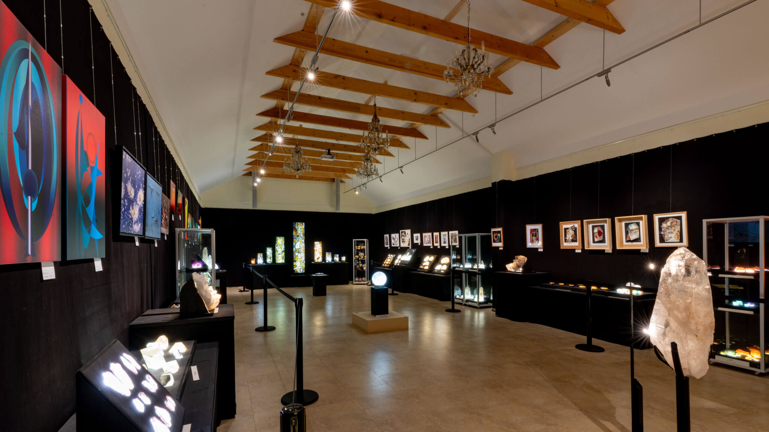 Moderne Kunstausstellung mit Gemälden und leuchtenden Kristallen in einem stilvollen, gut beleuchteten Raum.