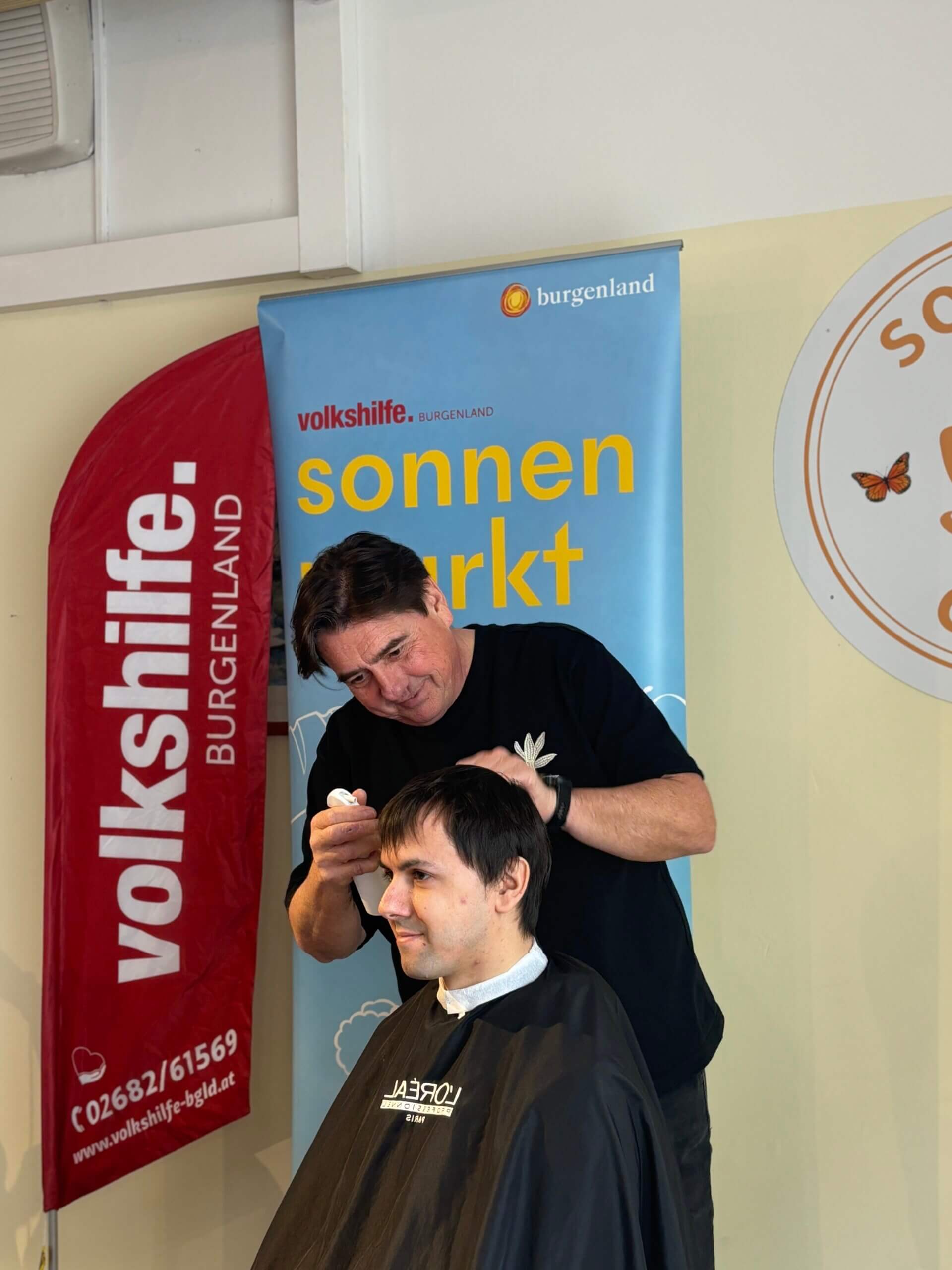 Friseur schneidet Haare eines Mannes beim Sonnenmarkt-Event der Volkshilfe Burgenland.