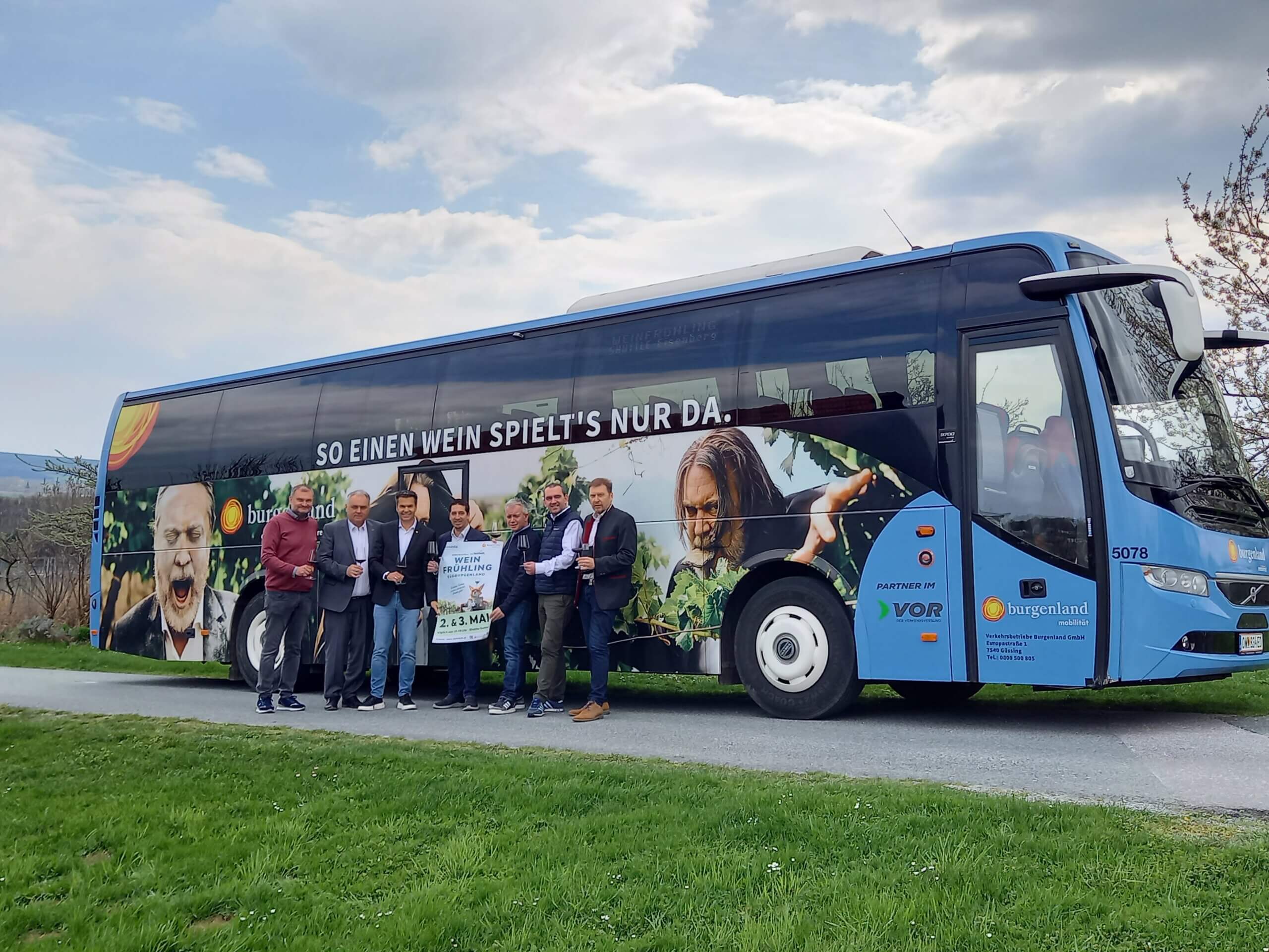 Gruppe vor Bus mit Weinwerbung im Burgenland, Frühlingswein-Event am 2. und 3. Mai.
