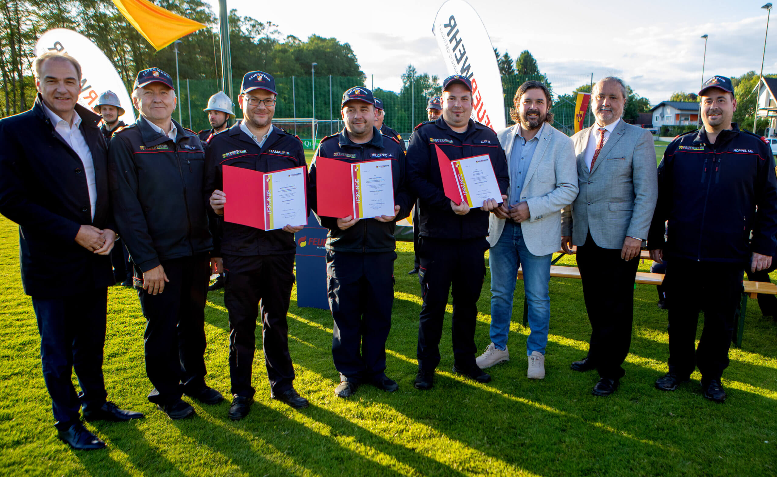 Feuerwehrmänner erhalten Auszeichnungen bei einer feierlichen Zeremonie im Freien.