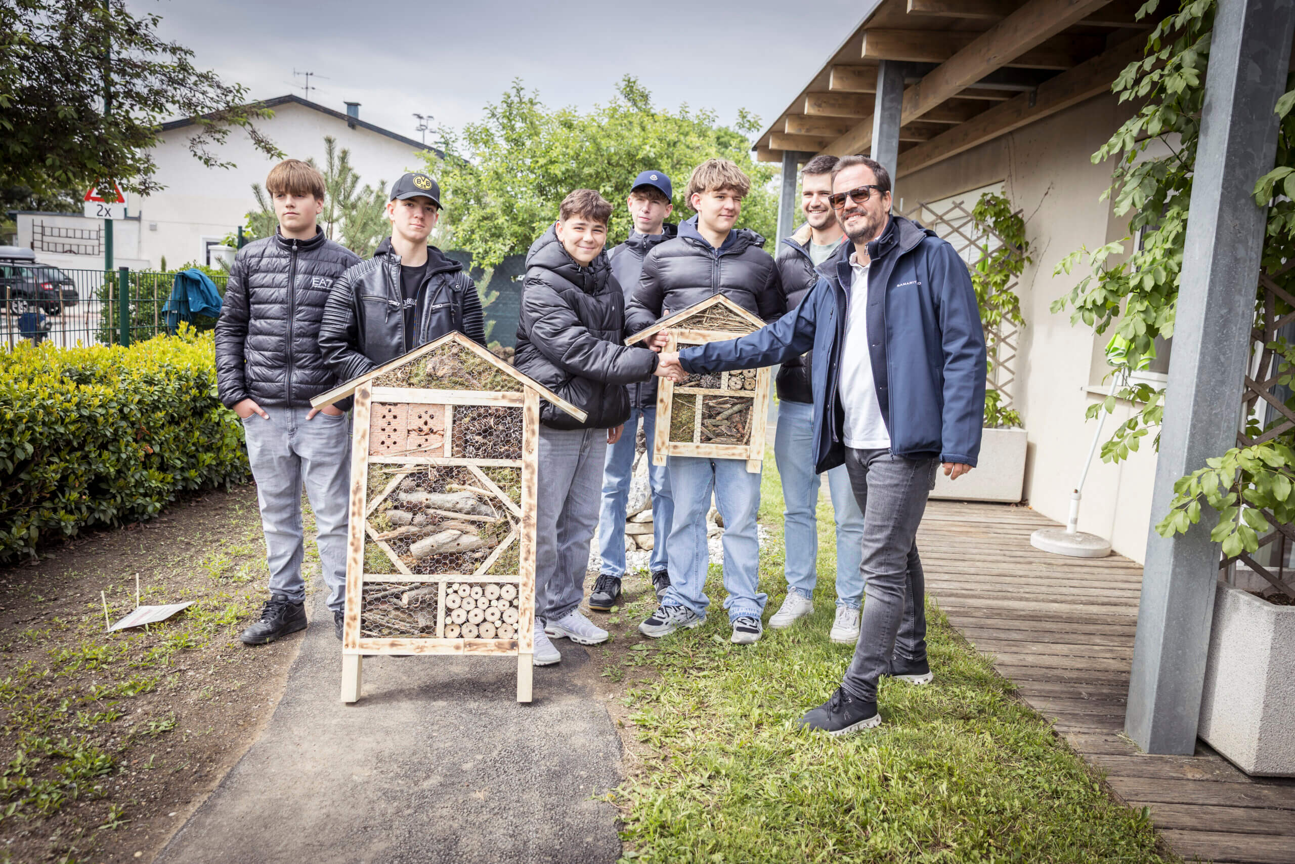 Gruppe von Jugendlichen baut und präsentiert Insektenhotels im Freien für Naturschutz und Umweltschutzbildung.