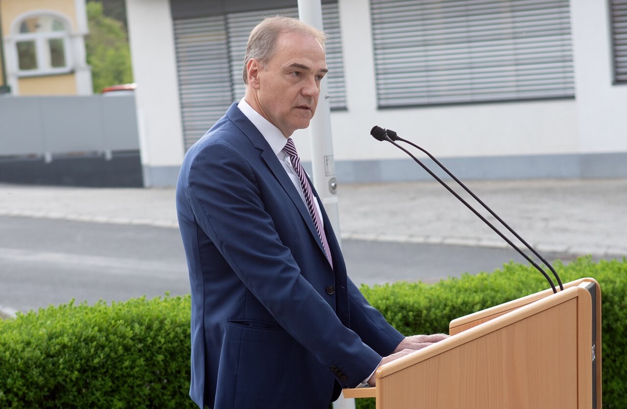 Mann in Anzug hält Rede am Rednerpult im Freien. Businessveranstaltung.