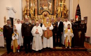 Kirchliche Zeremonie mit Priestern und Vertretern der Feuerwehr, Gruppenfoto vor einem kunstvollen Altar.