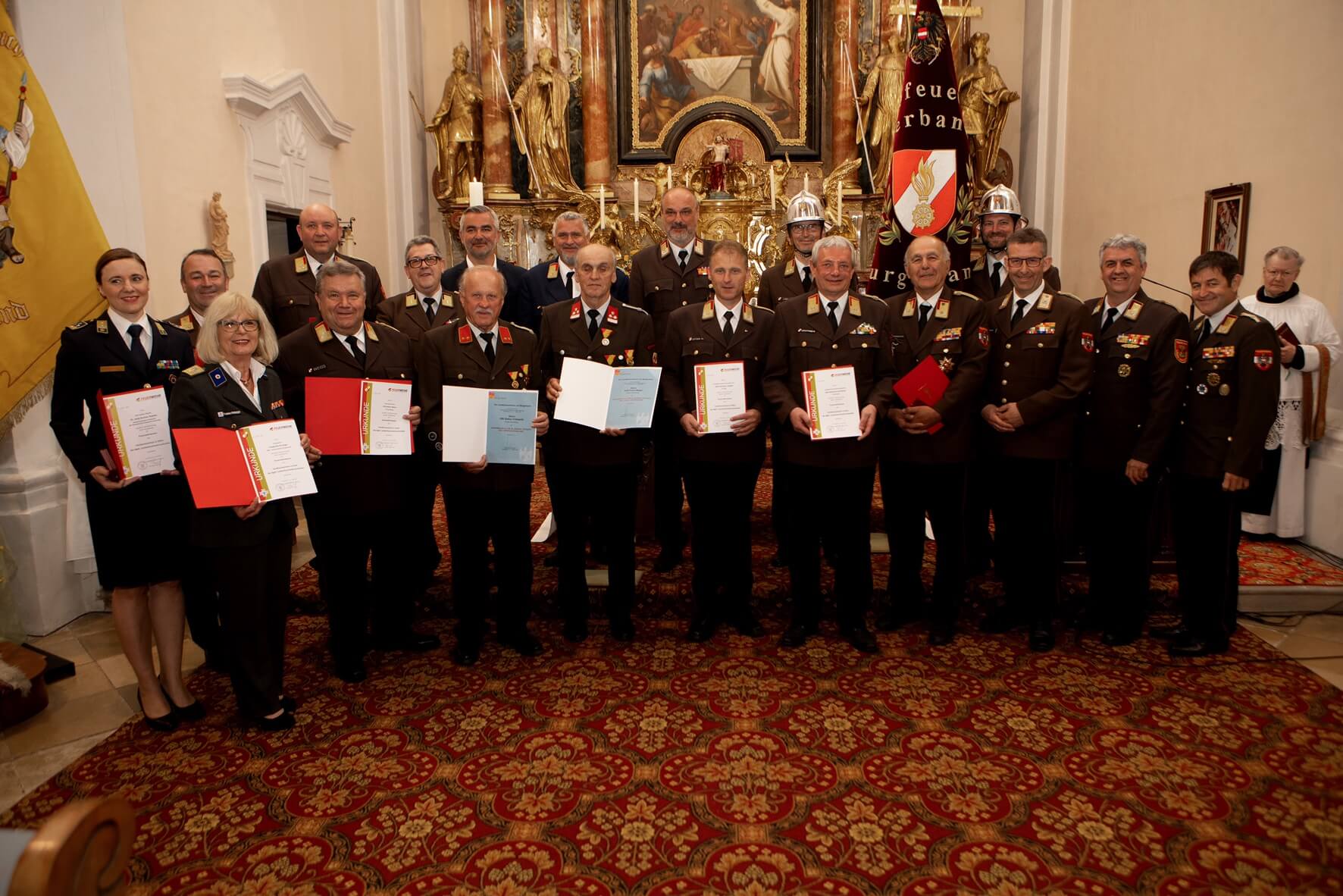 Feuerwehrleute erhalten Auszeichnungen in einer feierlichen Zeremonie in einer reich geschmückten Kirche.
