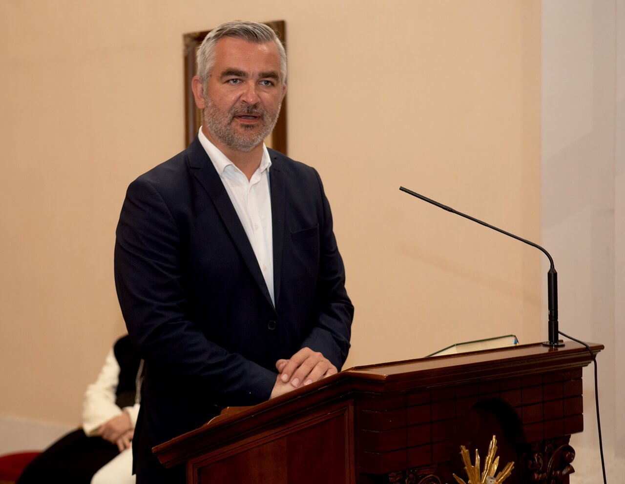 Ein Mann im Anzug spricht an einem Rednerpult bei einer Veranstaltung.