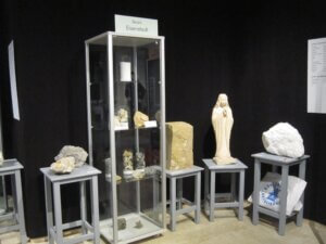 Vitrinen-Ausstellung mit Steinskulpturen und Felsen aus dem Bezirk Eisenstadt im Museum, umgeben von schwarzen Wänden.