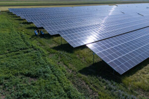 Luftaufnahme von Solarzellen auf einem grünen Feld, Energie-Mitarbeiter inspizieren die Photovoltaikanlage.