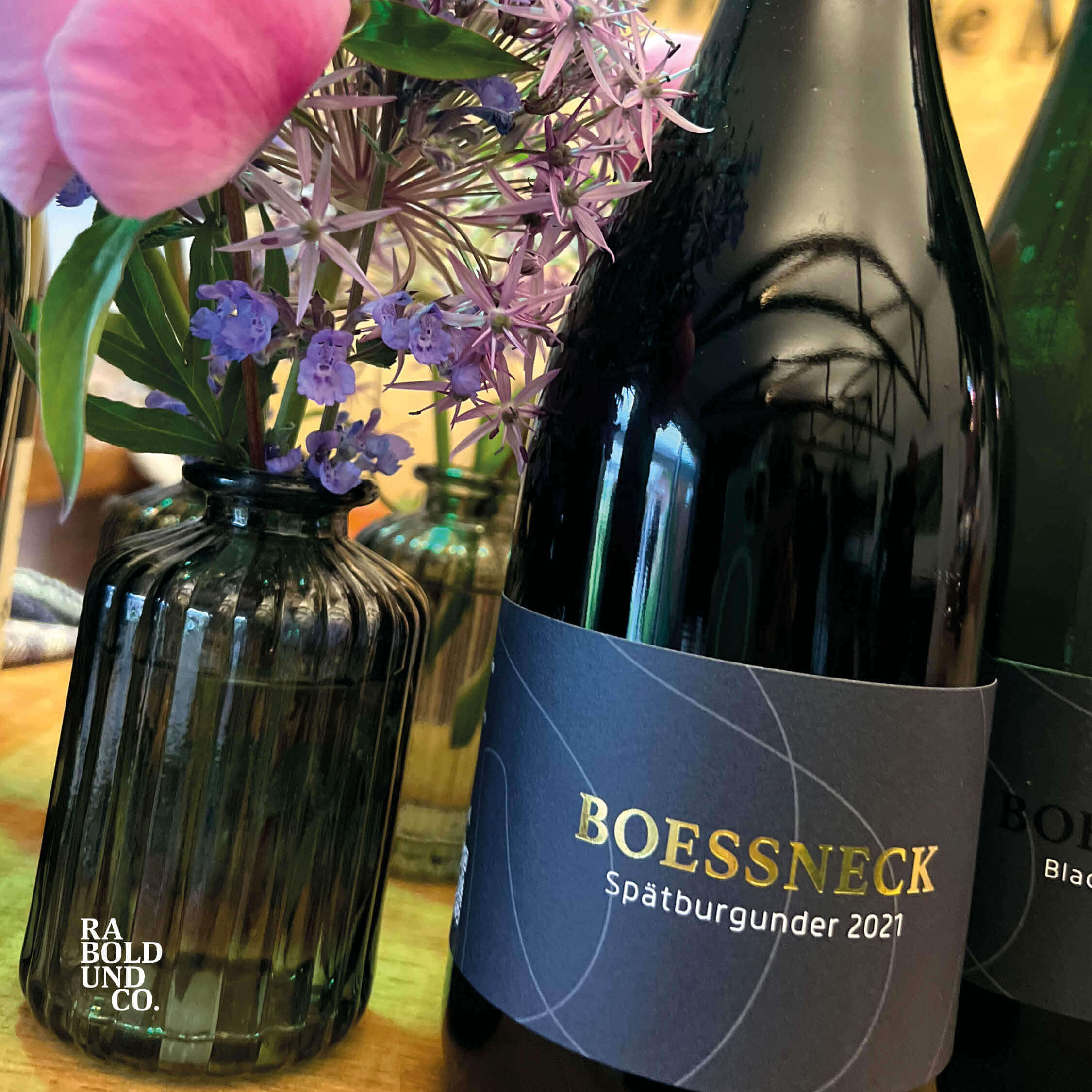 Spätburgunder 2021 von Boessneck neben einer Vase mit Blumen auf einem Tisch.