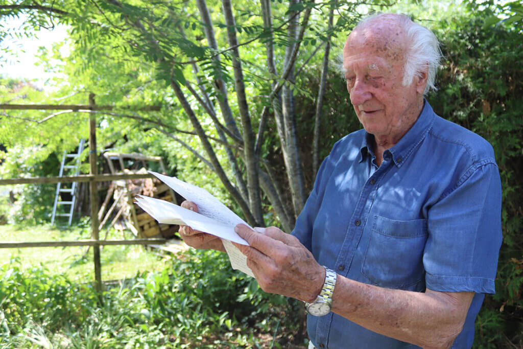 Brief Nöhrer©Nicole Matsch Älterer Mann liest unter Bäumen im Garten handgeschriebene Briefe an einem sonnigen Tag.