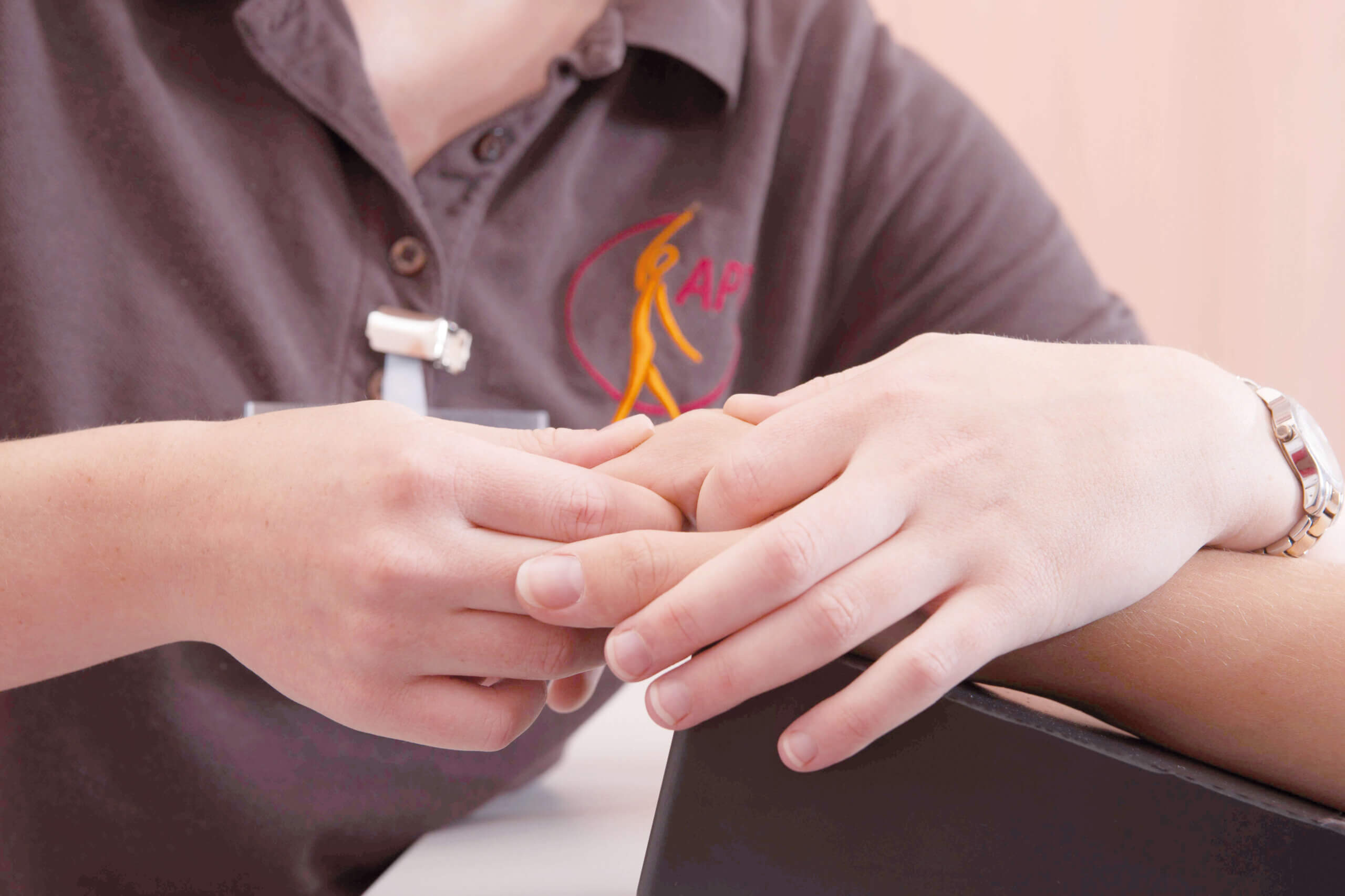 Pflegekraft hält die Hand einer Person zur Unterstützung und Fürsorge.