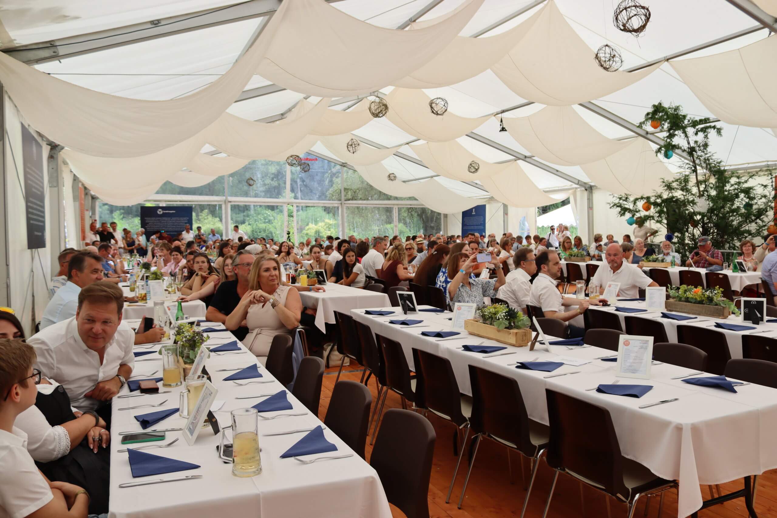 Feierliche Veranstaltung im Festzelt mit Gästen an festlich gedeckten Tischen.