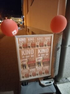 Filmveranstaltung Kino in der AK am 30. Juli, Plakataushang bei Nacht mit roten Luftballons dekoriert.