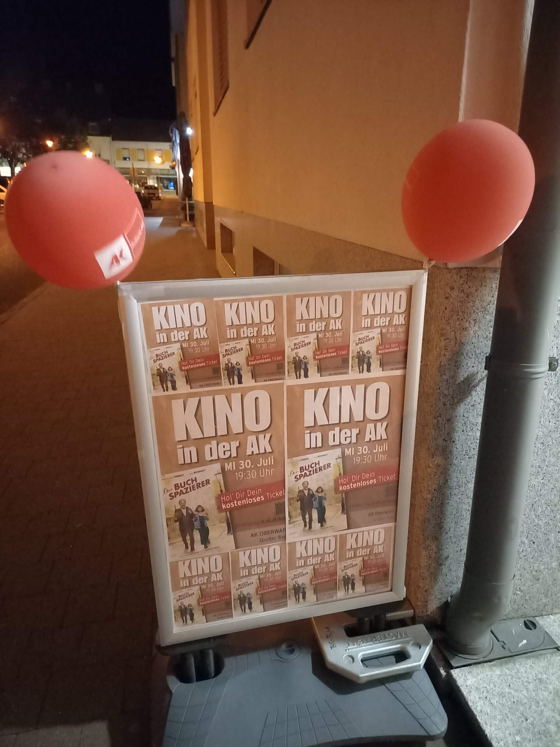 Filmveranstaltung Kino in der AK am 30. Juli, Plakataushang bei Nacht mit roten Luftballons dekoriert.