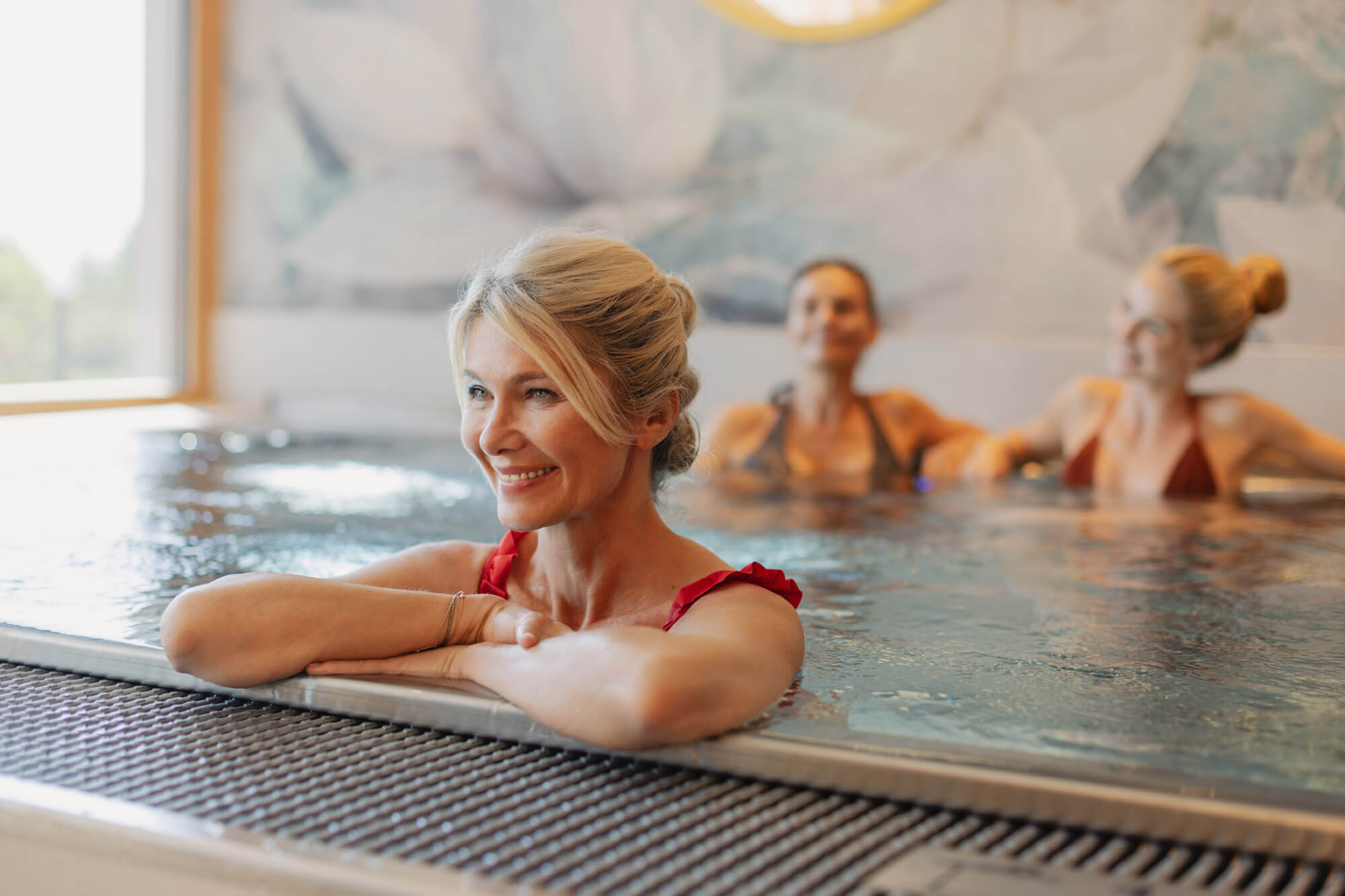Frau genießt Wellness im Whirlpool mit Freunden im Hintergrund, entspanntes Spa-Erlebnis.