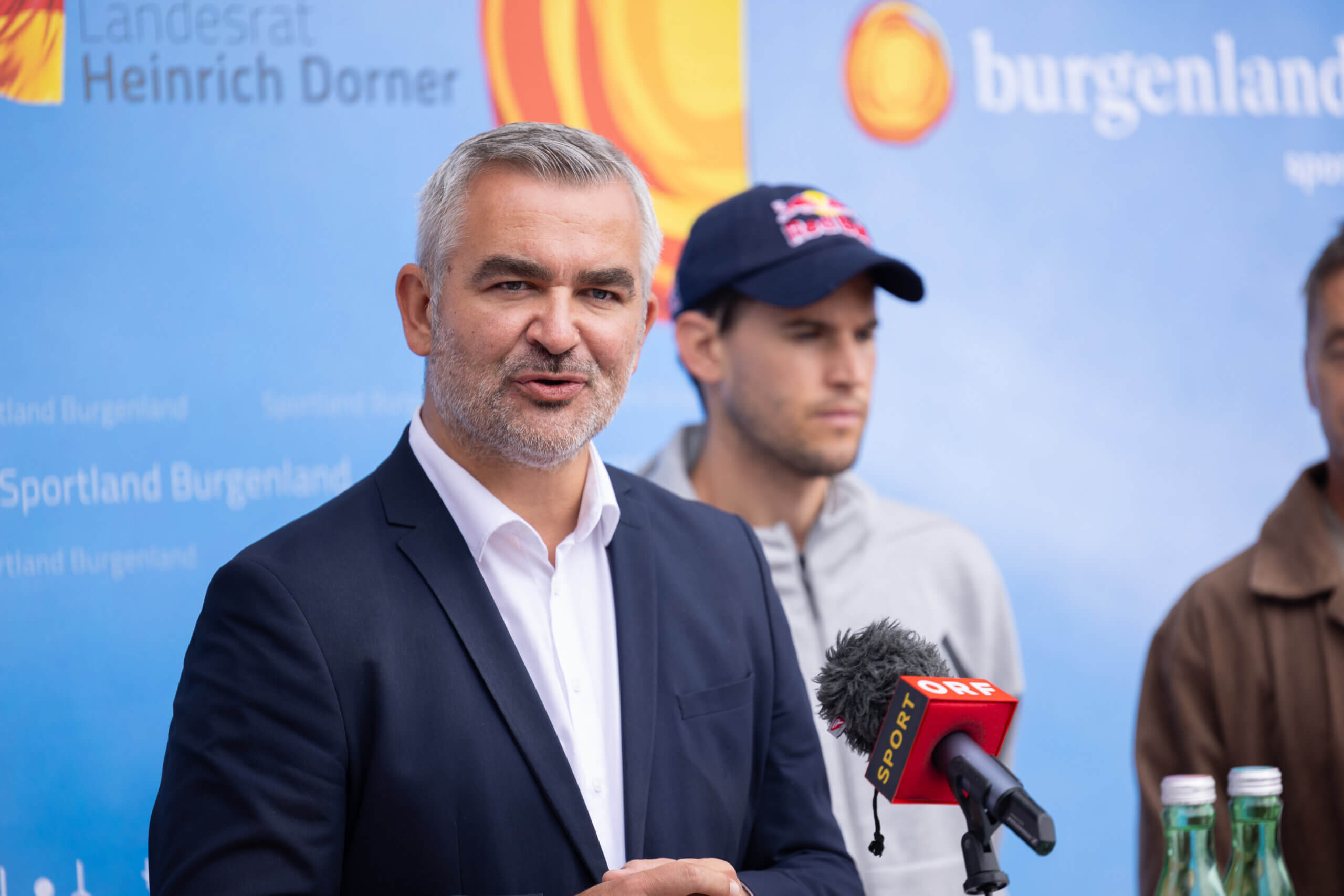 Mann spricht bei einer Pressekonferenz in Burgenland, Mikrofon von Sport ORF sichtbar.