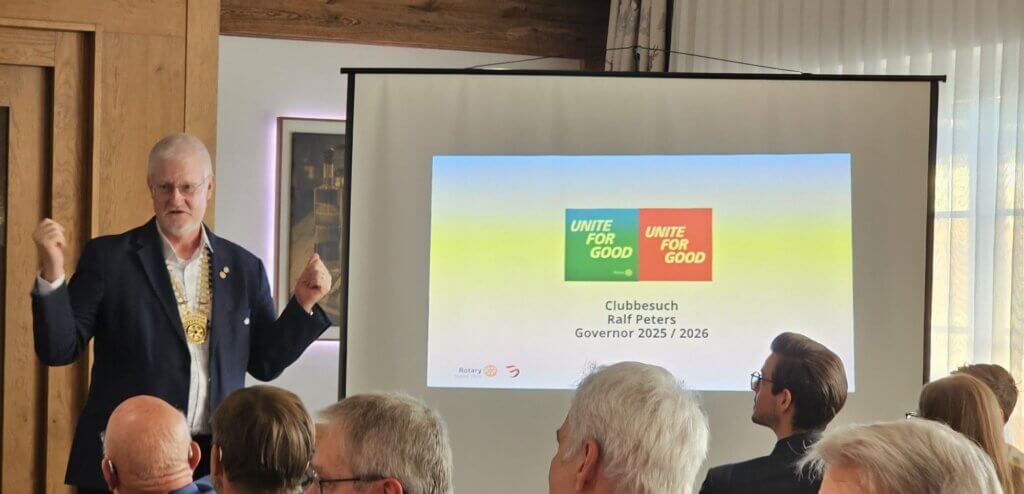 Eine Person hält einen Vortrag über Unite for Good bei einem Clubbesuch mit Präsentation.
