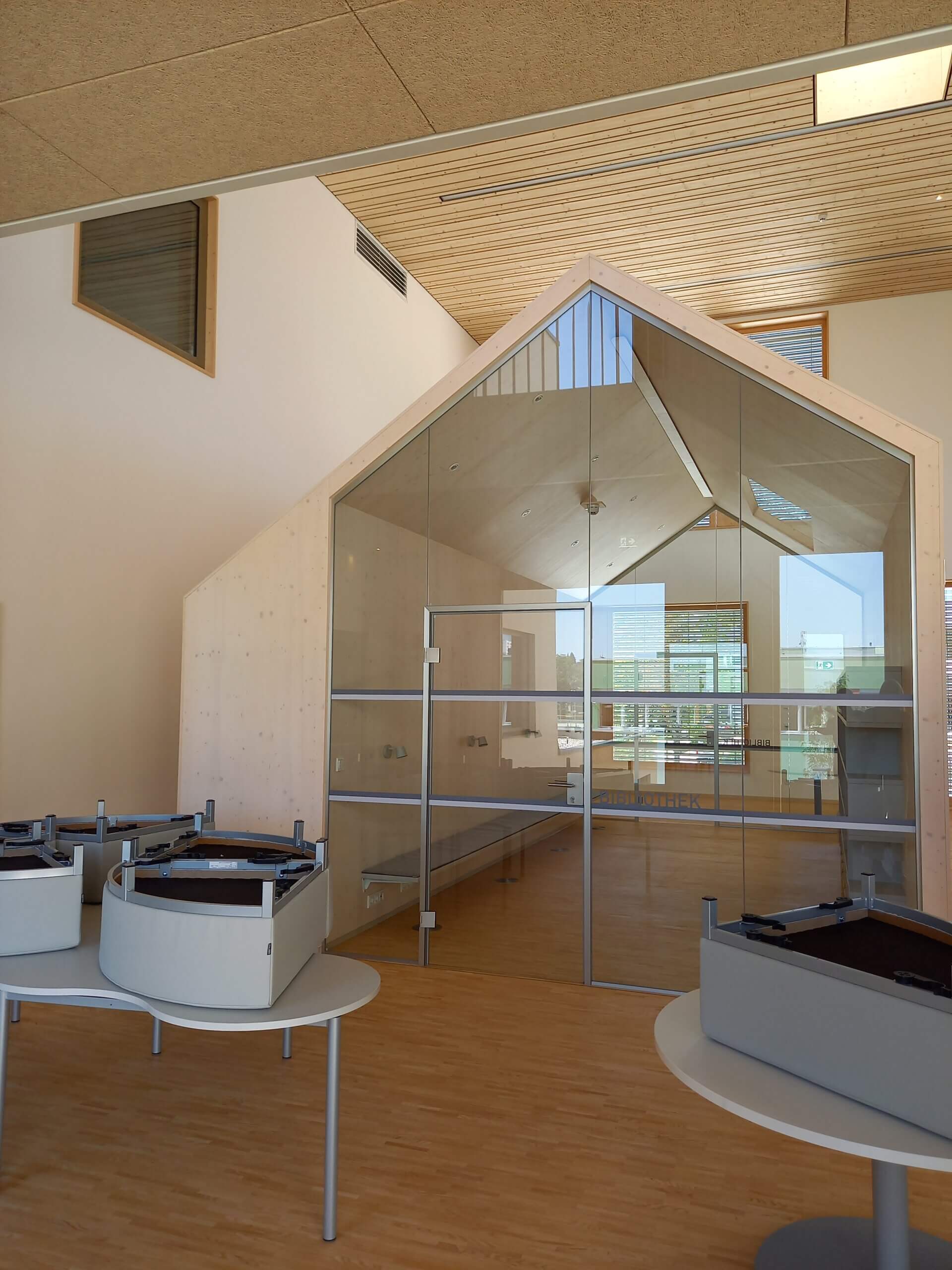 Moderner Innenraum mit Holzdecke, Glaswänden und leerem Besprechungsraum. Helle und minimalistische Architektur.